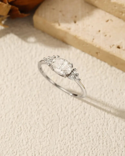 Sølvring med oval moissanite sat på tværs af fingeren og tre små zirkonia på hver skulder i 925 sterling sølv.