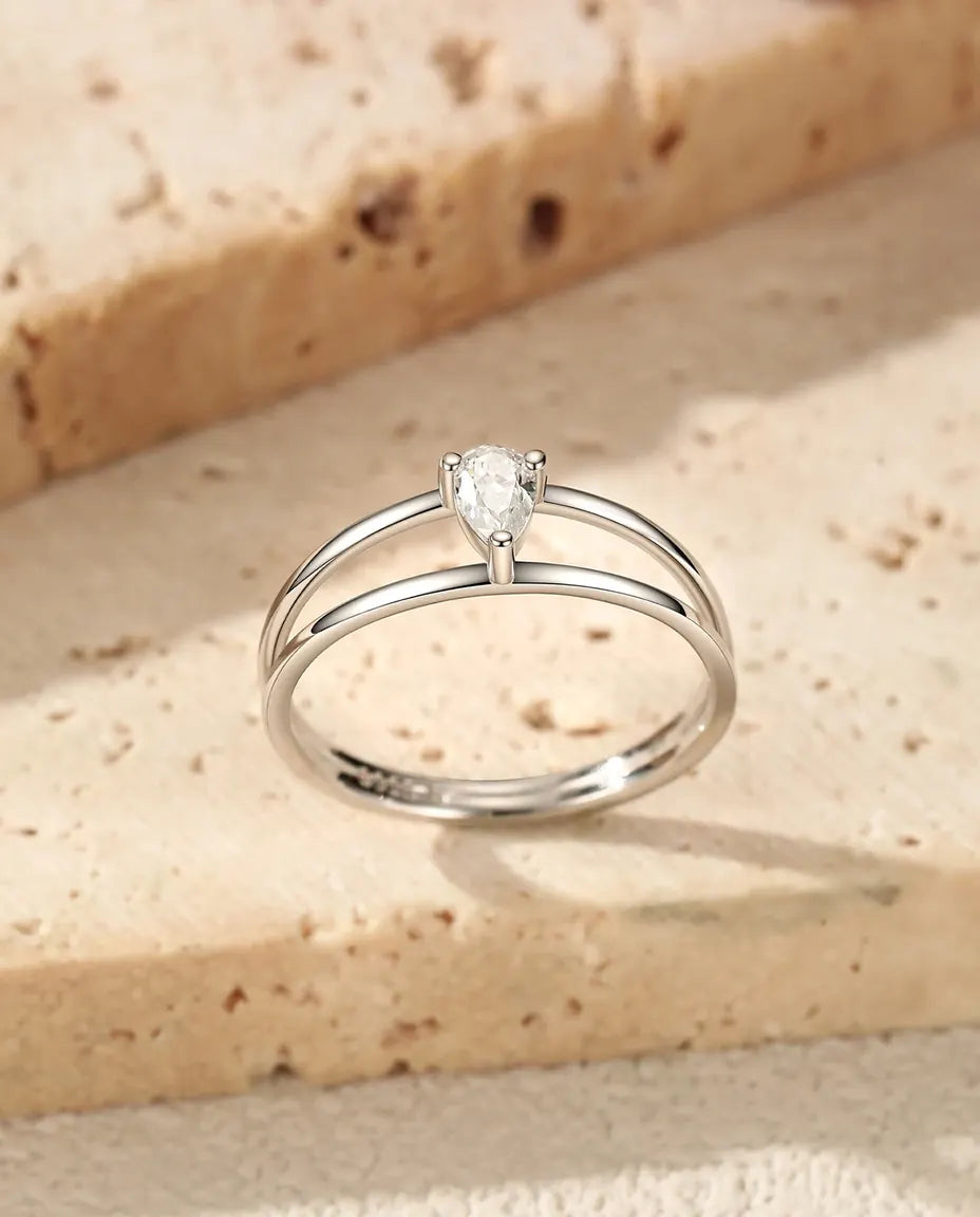 Sølvring med pæreslebet moissanite fattet på tværs mellem to tynde skinner i poleret 925 sterling sølv.