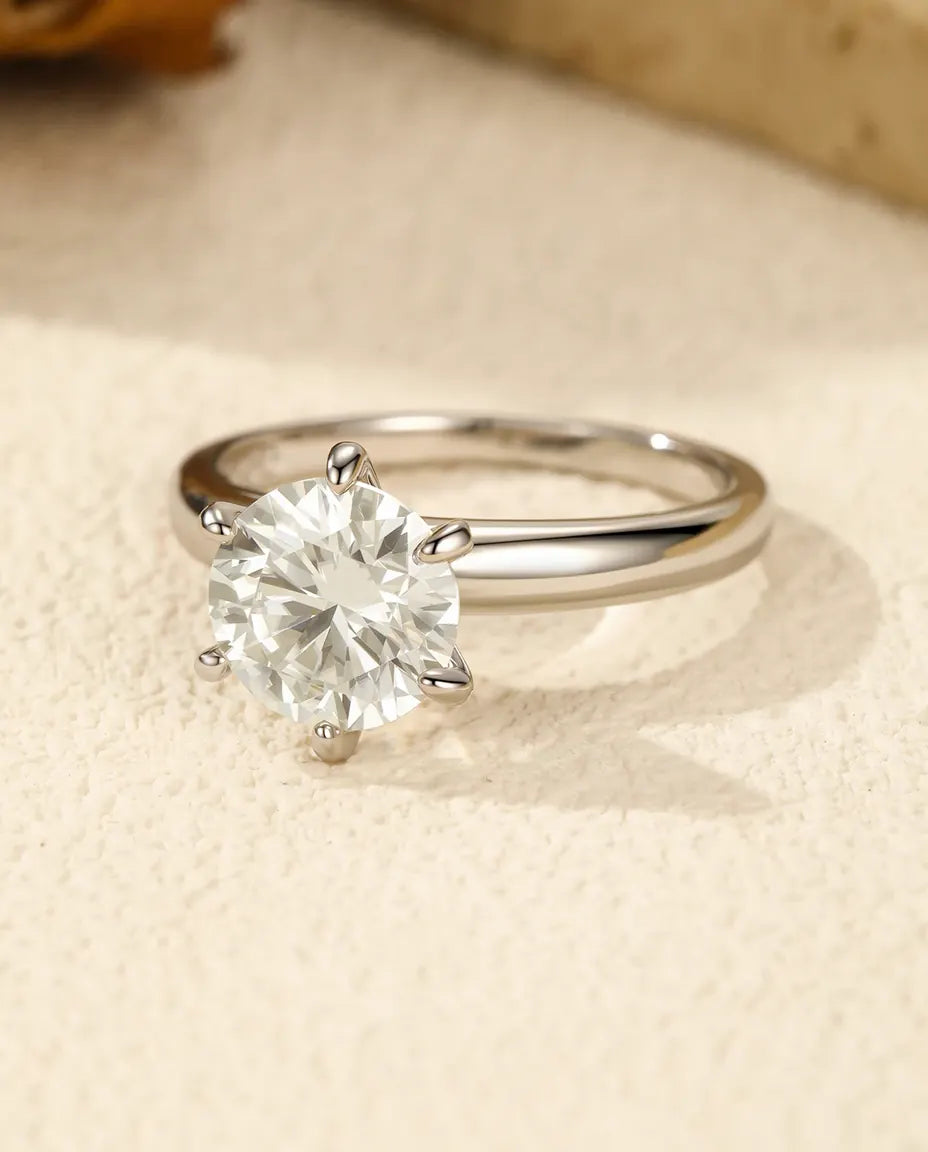 Solitærring i 925 sterling sølv med stor rund moissanite hævet i en kronefatning over en fin skinne.