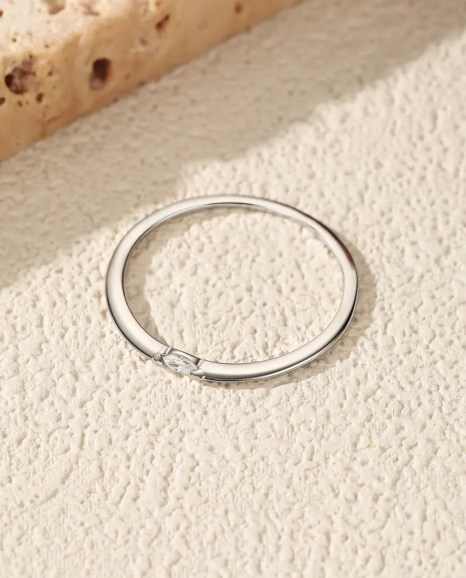 Smal sølvring med en enkelt marquiseslebet moissanite lagt på tværs af skinnen i poleret 925 sterling sølv.