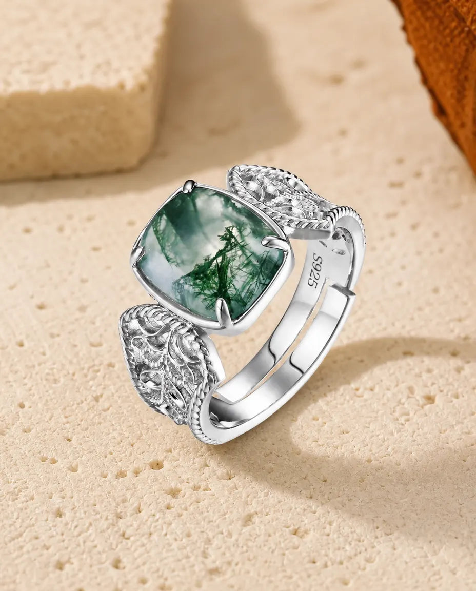 Stor cocktailring i 925 sterling sølv med pudeslebet moss agate-cabochon holdt af fire snoede klør og filigranskuldre.