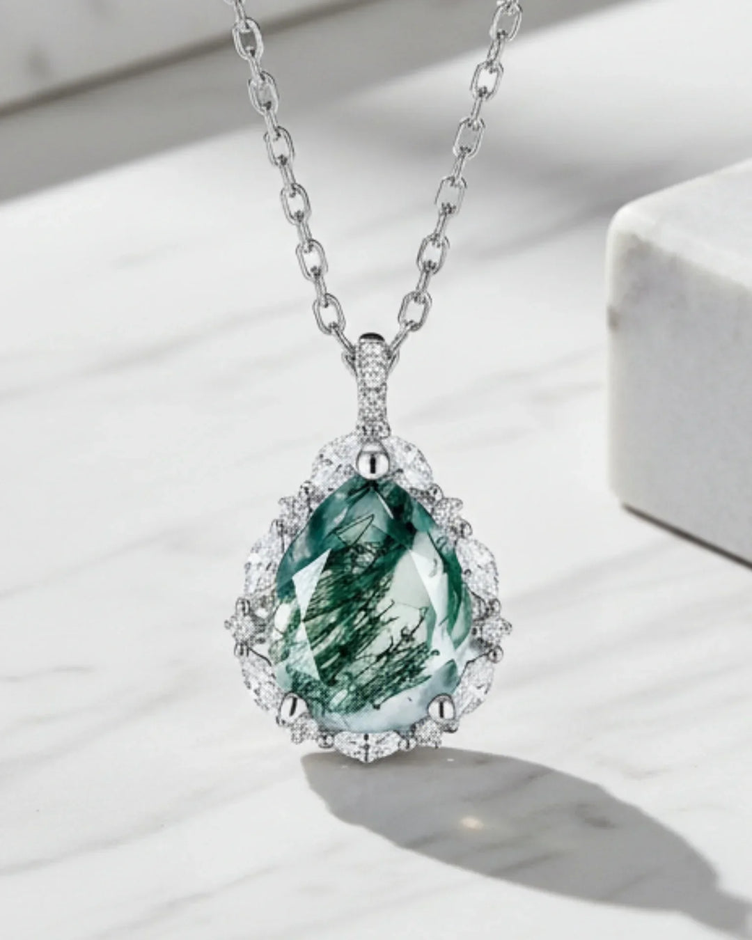 Pæreslebet grøn moss agate omkranset af en halo af zirkoner i et vedhæng af 925 sterling sølv.