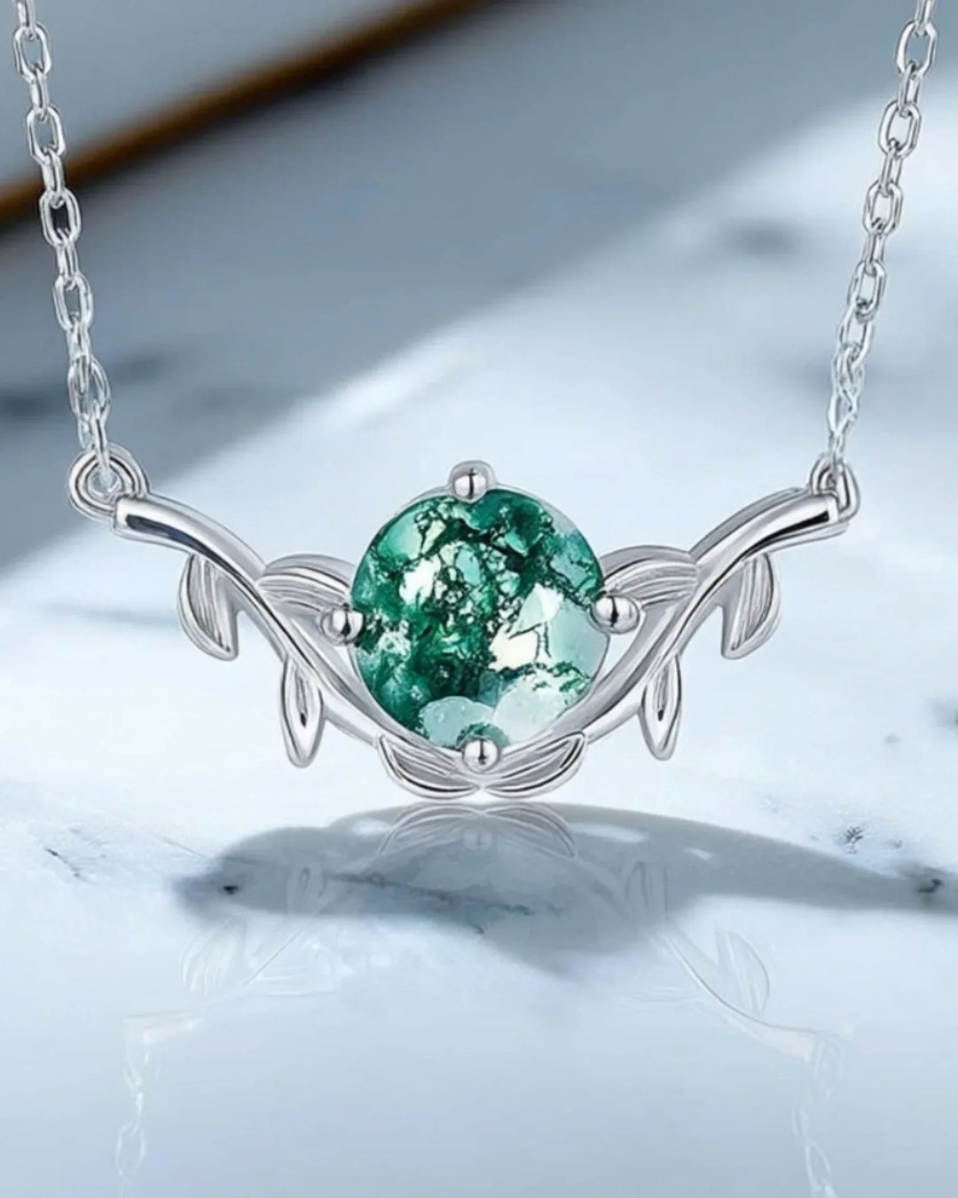 Rundslebet grøn moss agate i en fatning af blade og kviste i 925 sterling sølv på en fin kæde.
