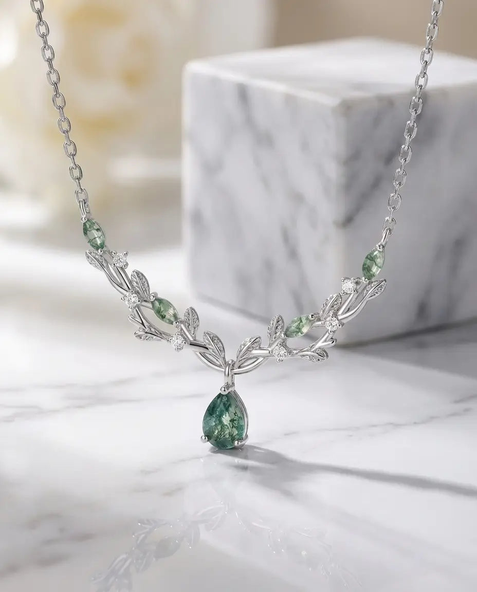 Vedhæng formet som en vinranke med blade, pæreslebet grøn moss agate og hvide zirkoner i lyst sølv.
