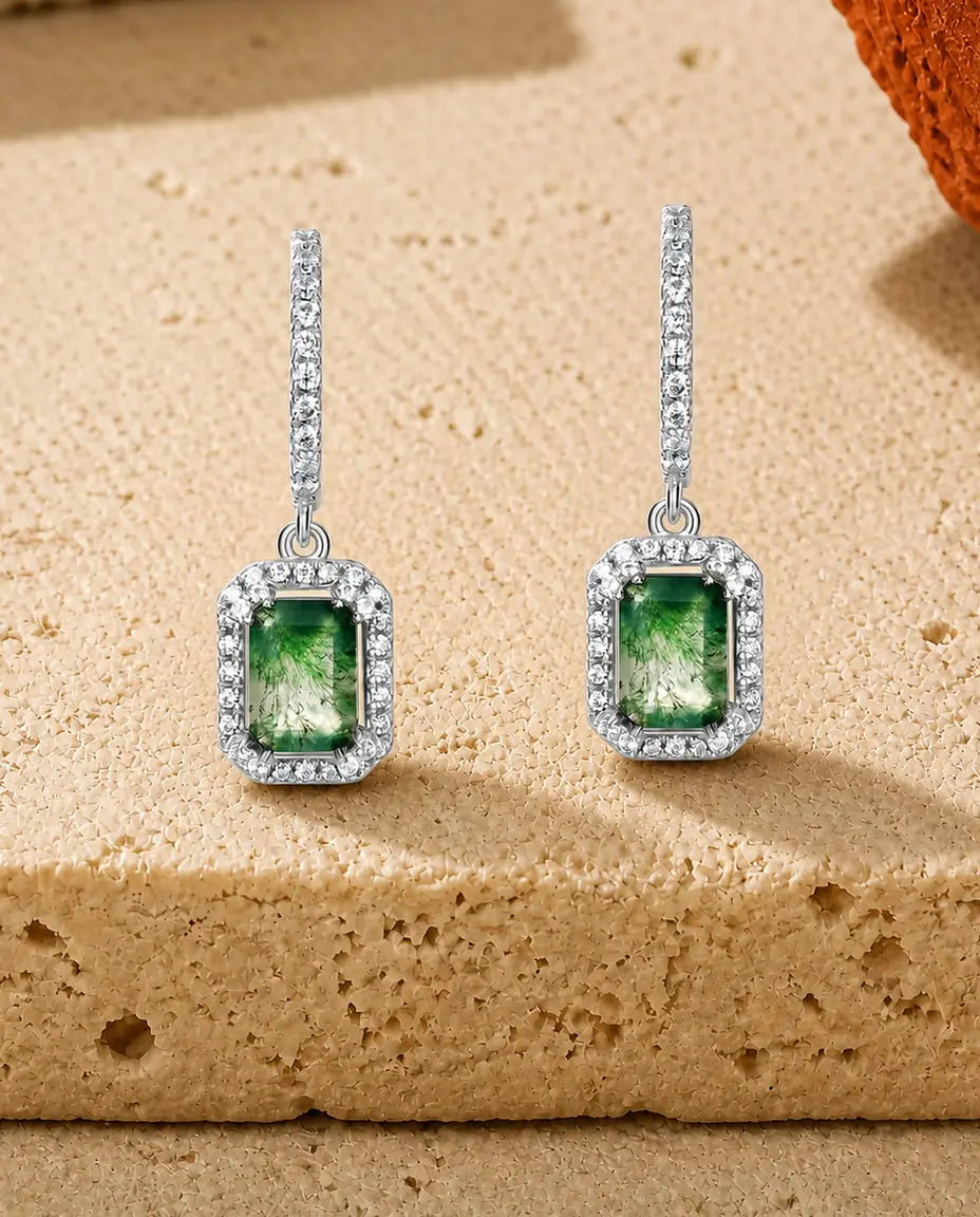 Øreringe med smaragdslebet grøn moss agate i zirkonia-halo hængende for enden af en buet pavélinje.