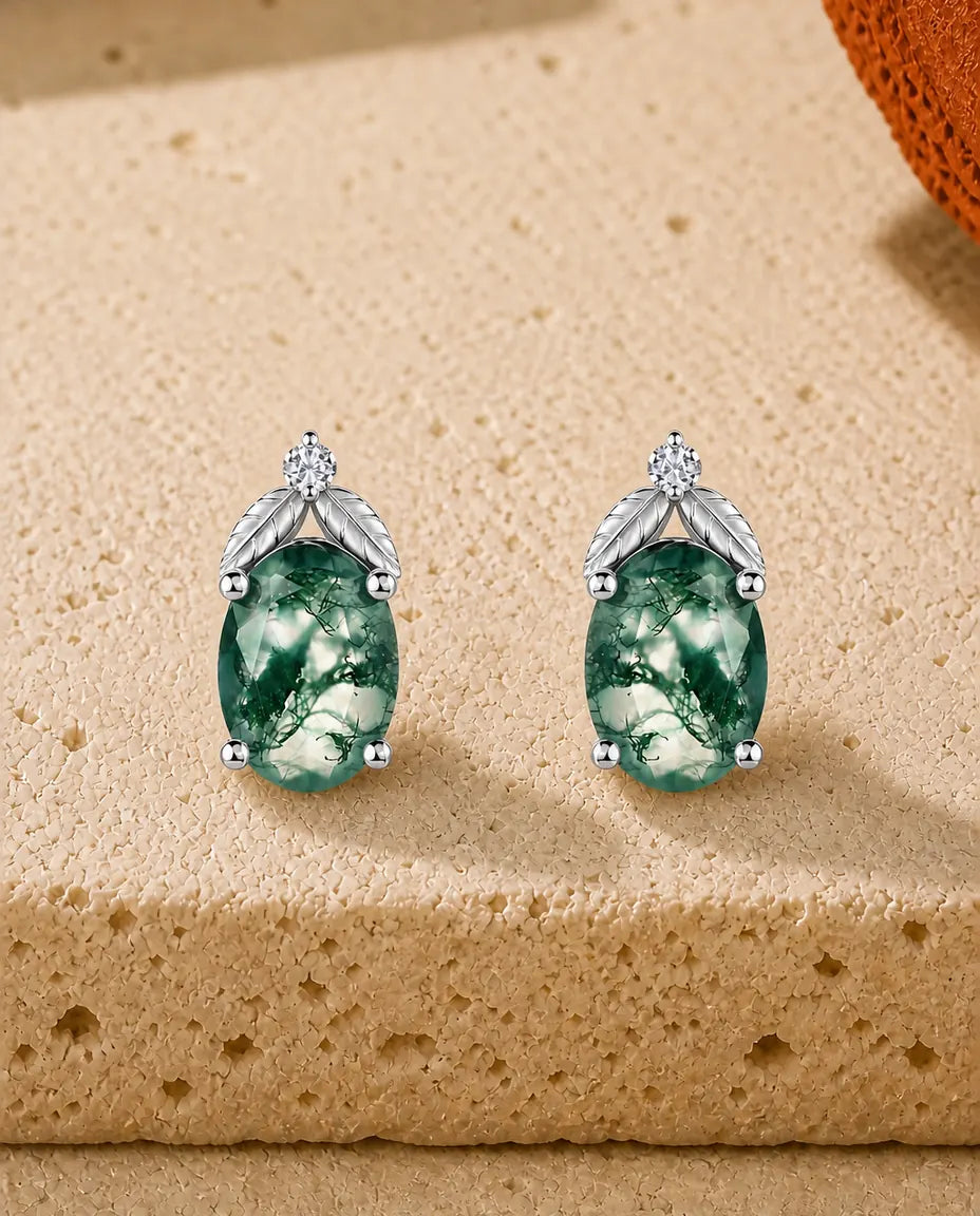 Ovale ørestikker med grøn Moss Agate under to ribbede sølvblade og en lille klar zirkon foroven.