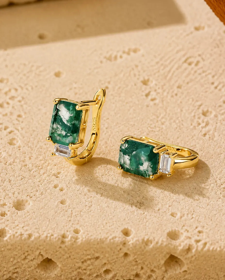 Små guldbelagte creoler med en stor smaragdslebet grøn moss agate og en aflang klar sten nedenunder.