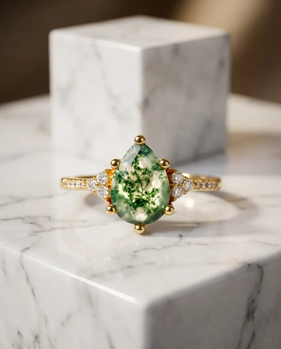 Ring med pæreslebet grøn moss agate på 6x8 mm og tre runde zirkoner i hver skulder, i sølv eller guld.