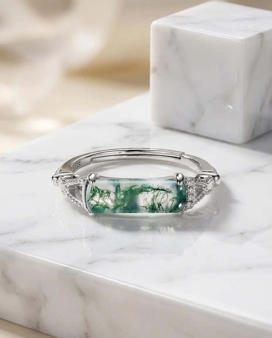 Justerbar hvidguldbelagt ring med rektangulær grøn moss agate på tværs og filigranskuldre med zirkoner.