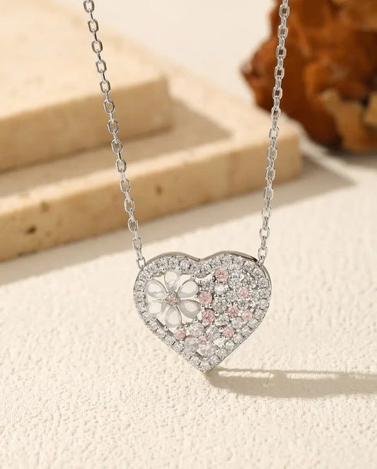 Hjertevedhæng i 925 sterling sølv med en blomst af perlemor og lyserøde og klare zirkoner.